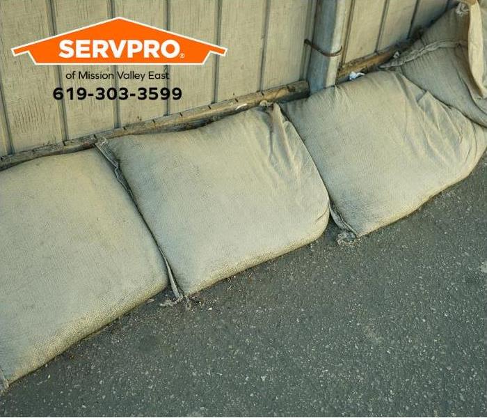 Sandbags are positioned next to a fence to prevent storm water from entering a home.